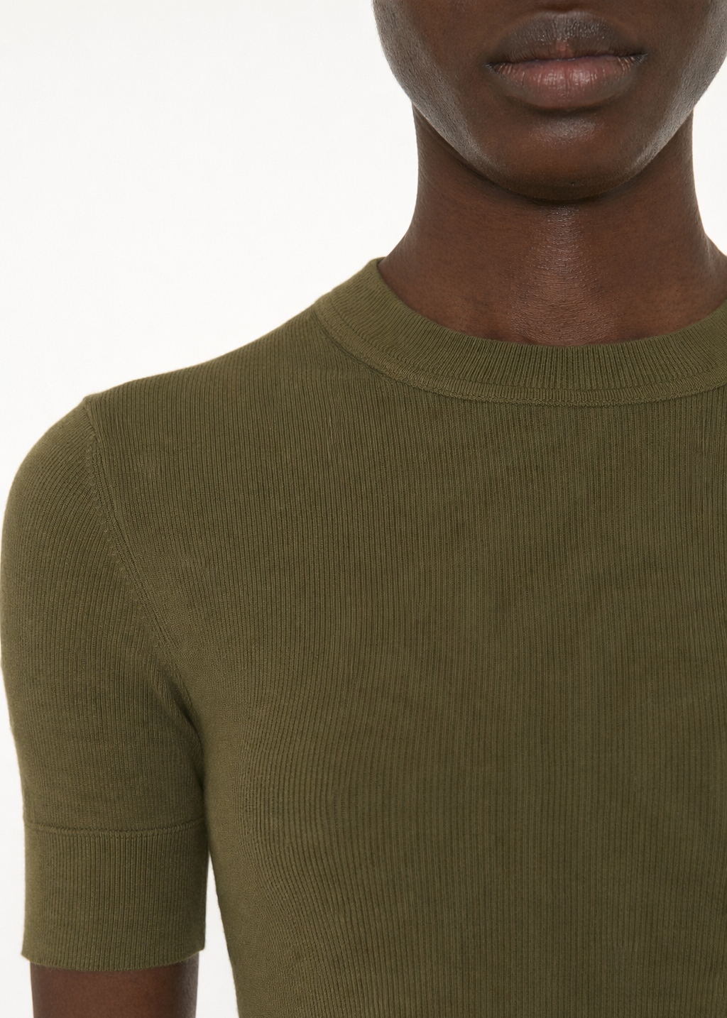 Person wearing a green ribbed sweater on a white background