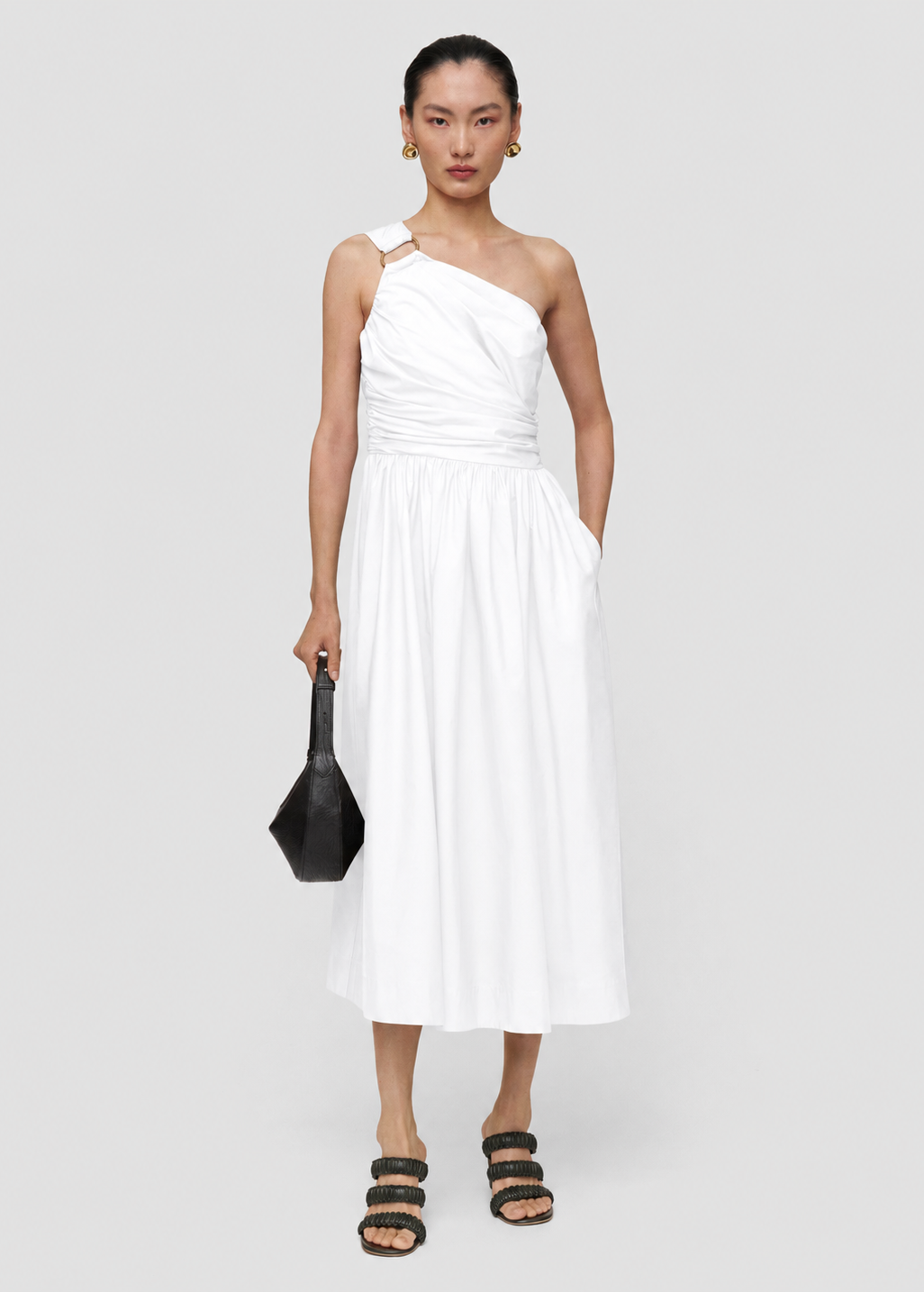 Woman wearing a white one-shoulder dress on a plain background