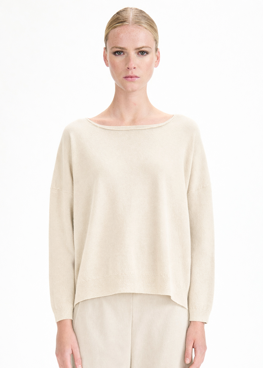 Woman wearing a beige sweater and pants on a white background