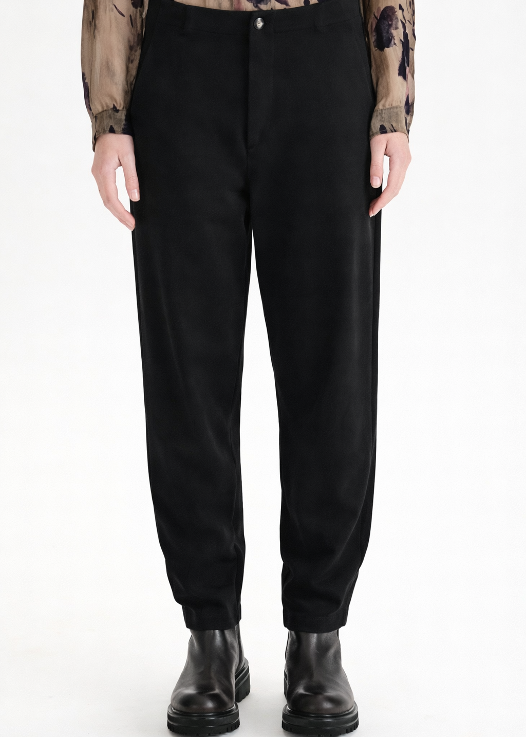 Person wearing black pants and black shoes on a white background