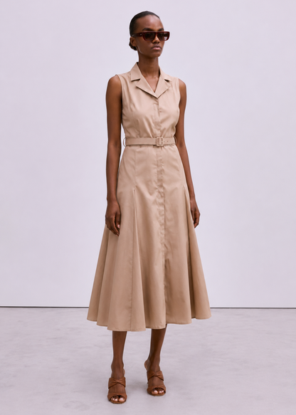 A model wearing a sleeveless beige midi dress with a collar, button front, and matching belt, styled with brown strappy sandals and dark sunglasses against a light gray studio background.