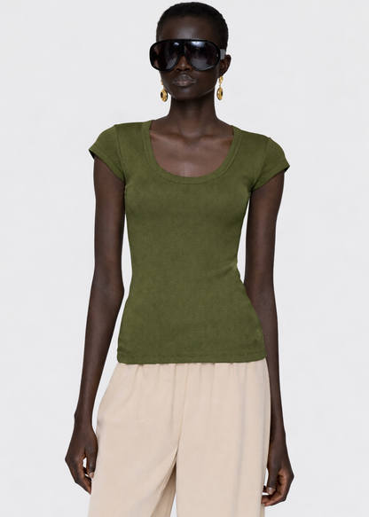 Woman wearing a green top and beige pants against a white background