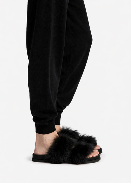 Person wearing black fluffy slippers on a white background
