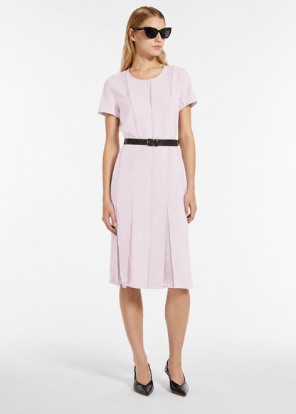 Woman wearing a light pink dress with a belt on a white background