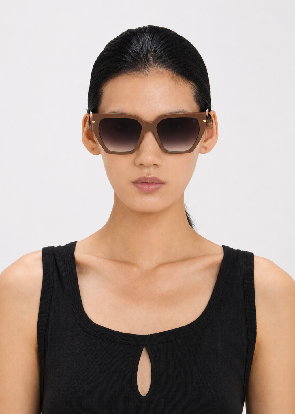 Woman wearing dark sunglasses against a light gray background