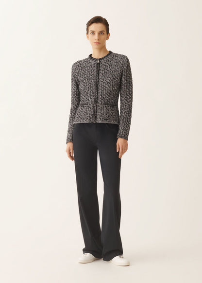 Woman wearing a patterned jacket and black pants on a white background