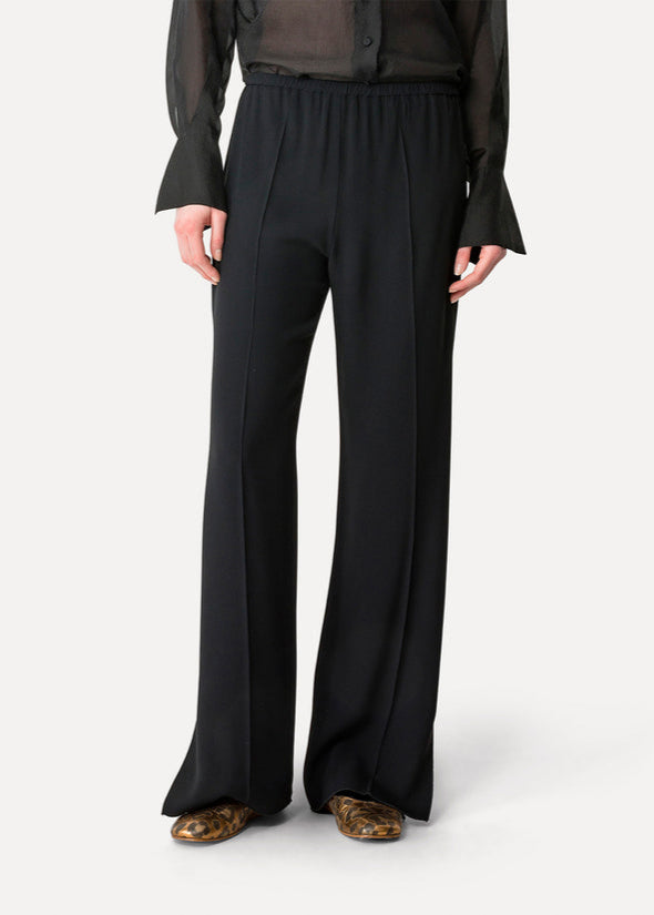 Person wearing black wide-leg pants on a white background