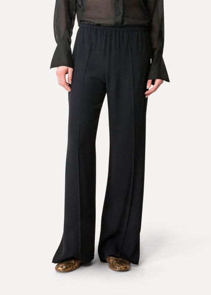 Person wearing black wide-leg pants on a white background