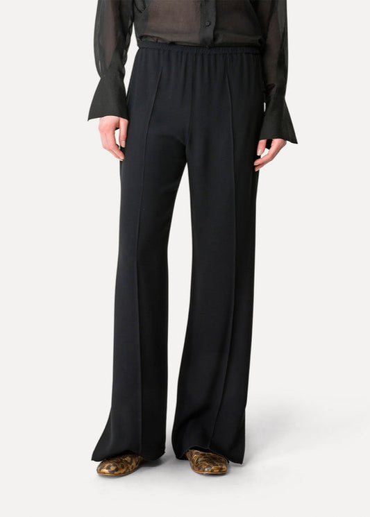 Person wearing black wide-leg pants on a white background