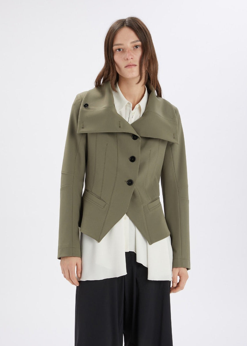 Woman wearing a green coat over a white shirt on a white background