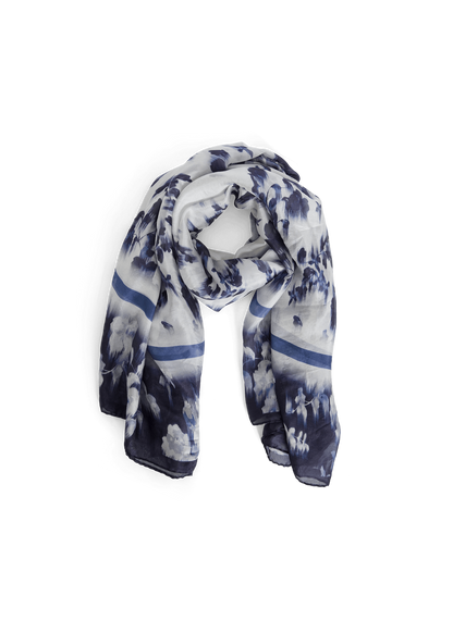 A lightweight scarf with a blue and white mountain landscape print, styled in a loop on a solid green background.