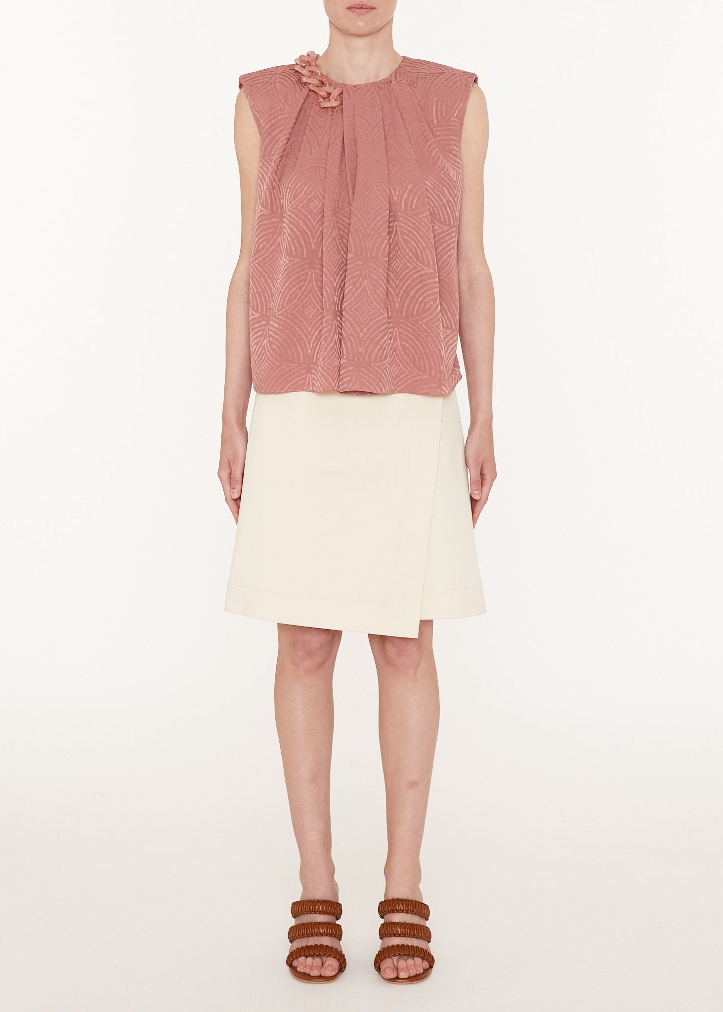 Woman wearing a pink sleeveless top and white skirt on a white background