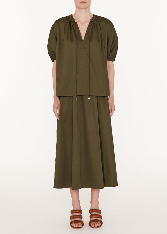 Person wearing an olive green outfit with a top and skirt on a white background