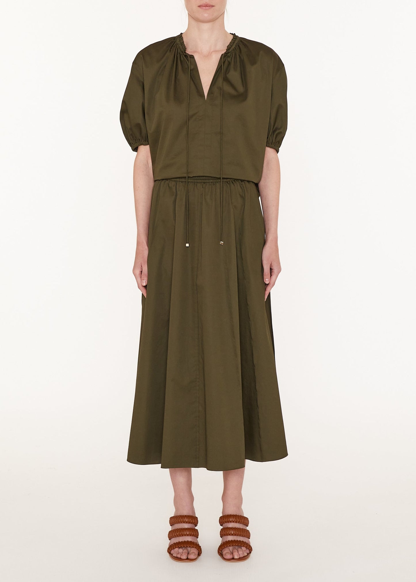 Person wearing an olive green dress on a white background