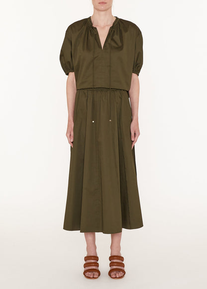 Person wearing an olive green dress on a white background
