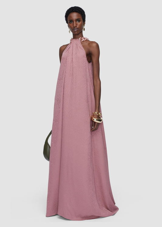 Woman wearing a long pink dress on a white background