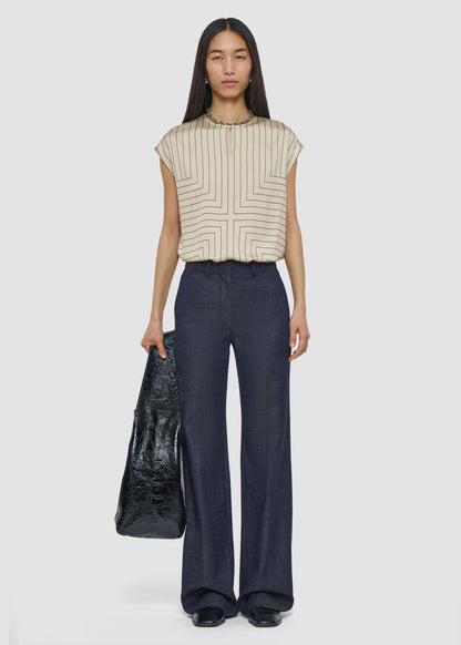 Woman wearing a striped top and dark pants holding a black bag on a white background