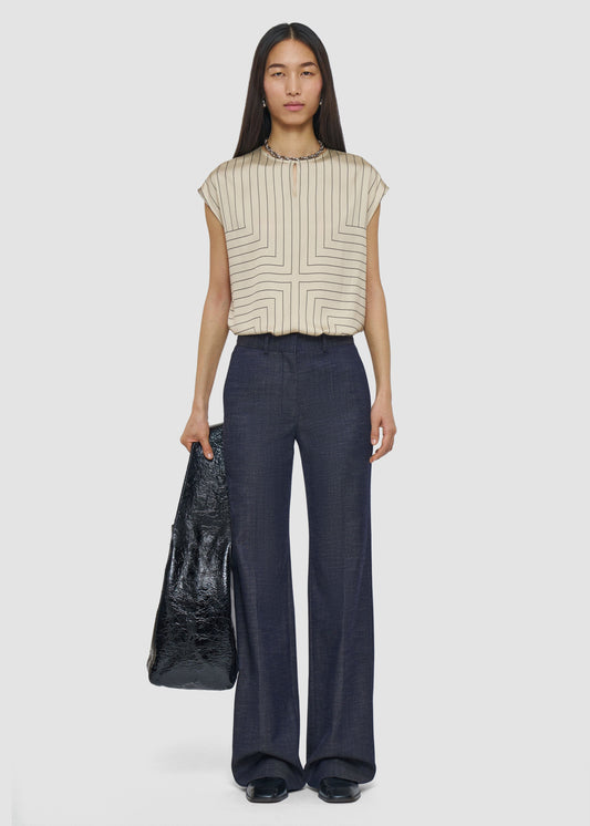 Woman wearing a striped top and dark pants holding a black bag on a white background