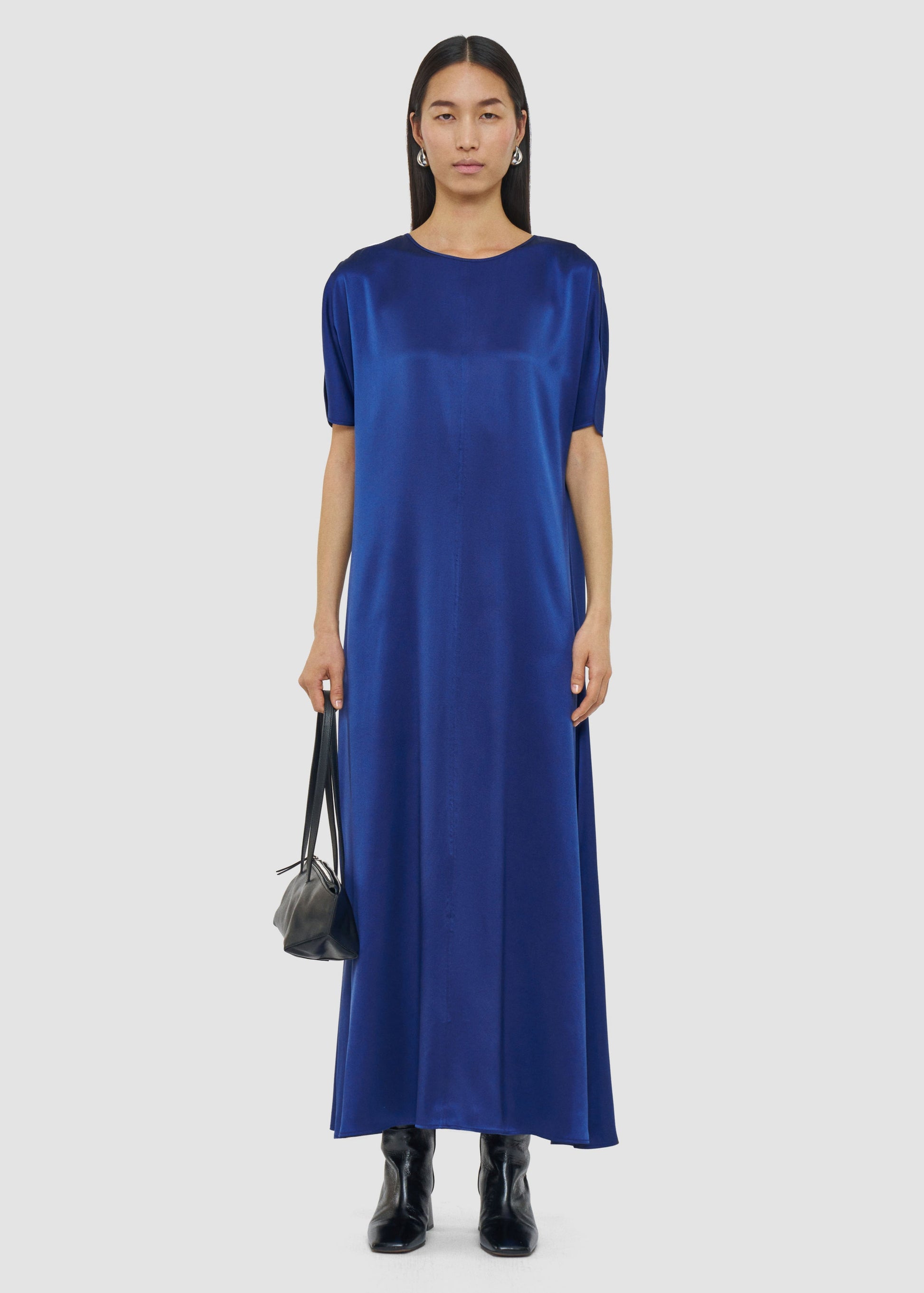 Woman wearing a blue dress holding a black handbag on a white background