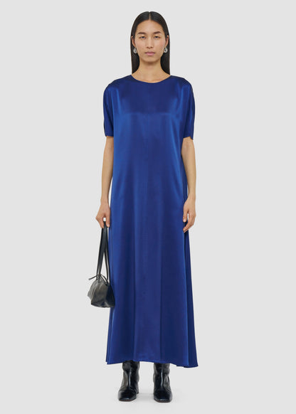 Woman wearing a blue dress holding a black handbag on a white background