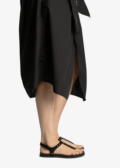 Person wearing a black dress and sandals on a white background