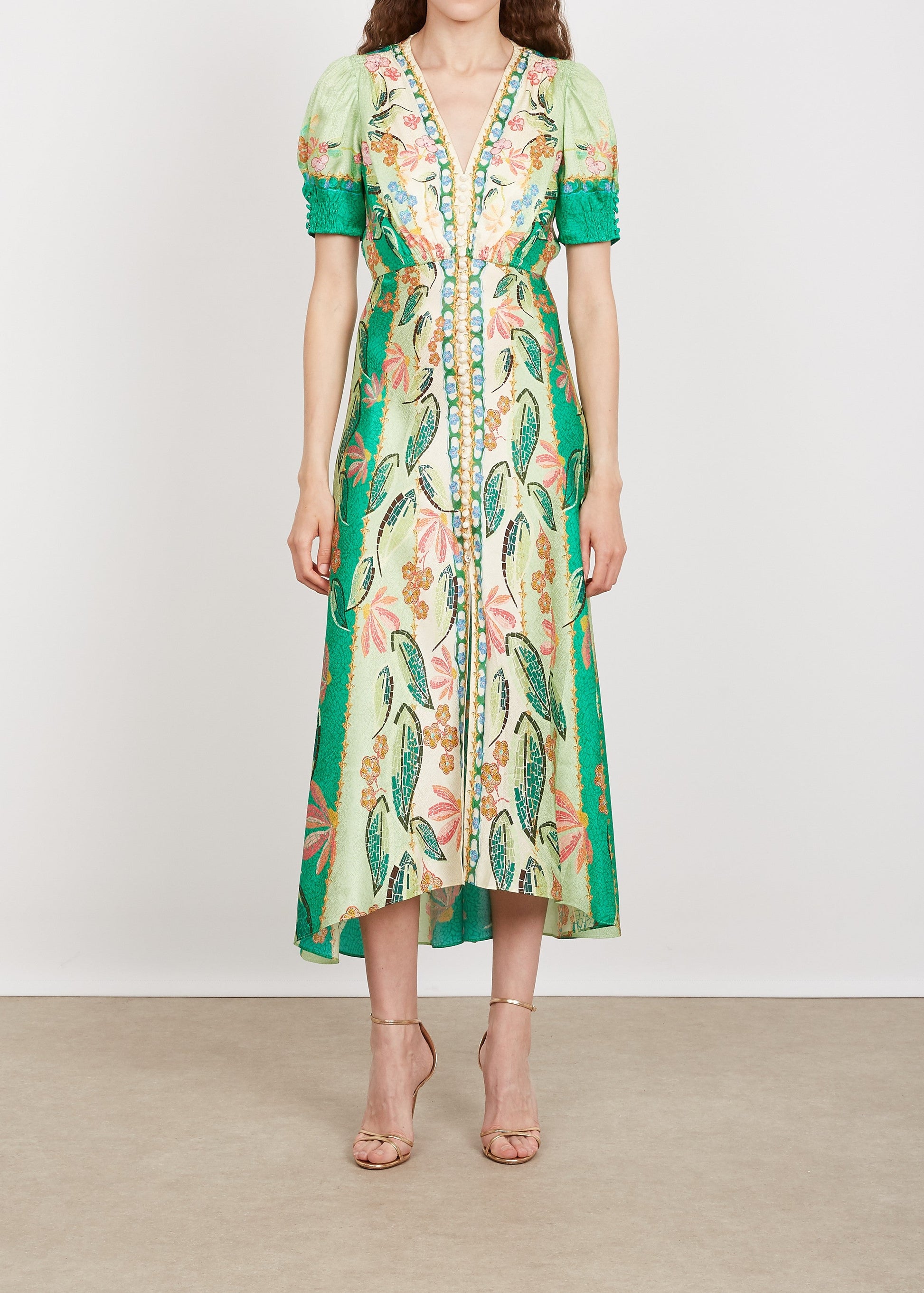 Woman wearing a floral dress with green accents on a plain background