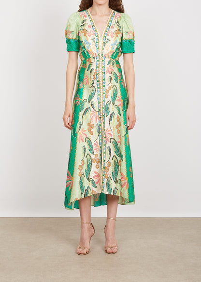 Woman wearing a floral dress with green accents on a plain background