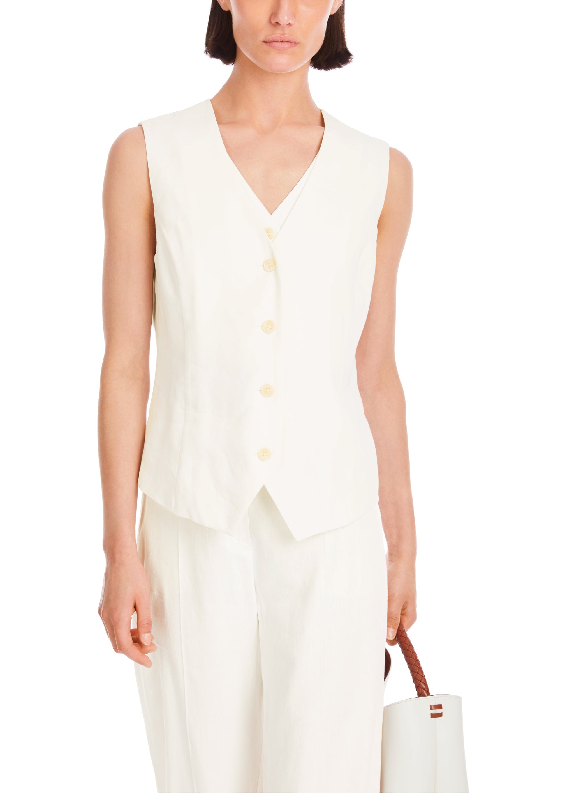 Woman wearing a white sleeveless dress with buttons on a white background