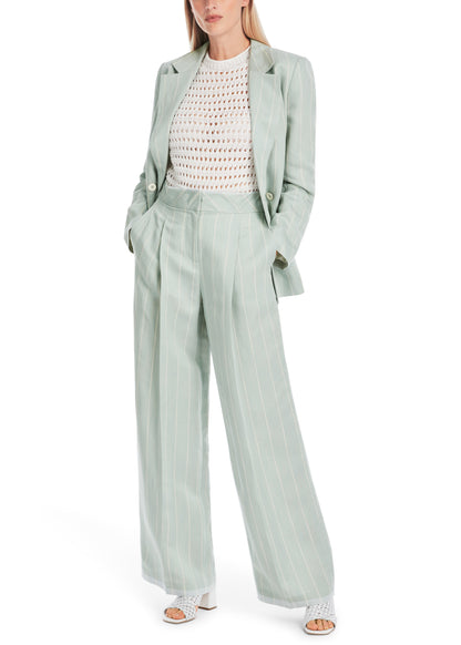 Woman wearing a light green suit with a white top on a white background