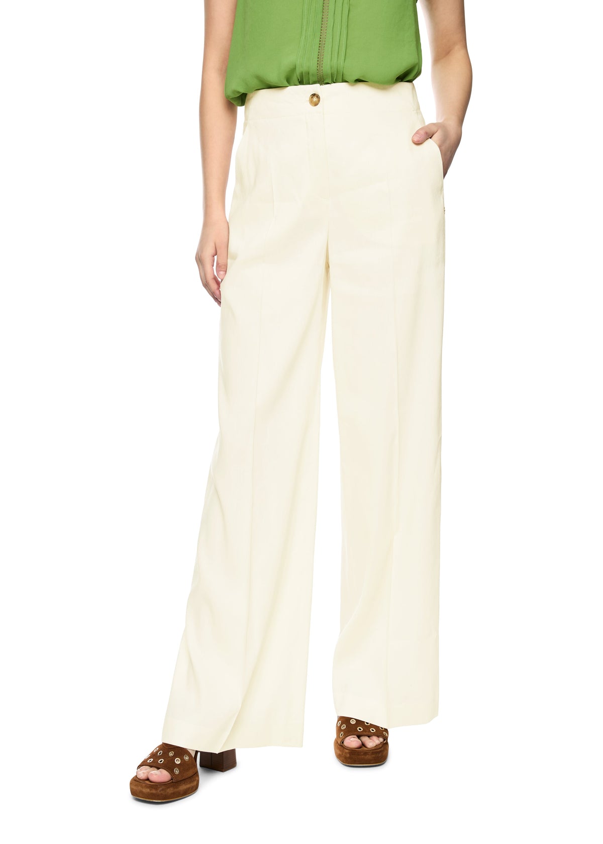 Person wearing white wide-leg pants with a green top on a white background