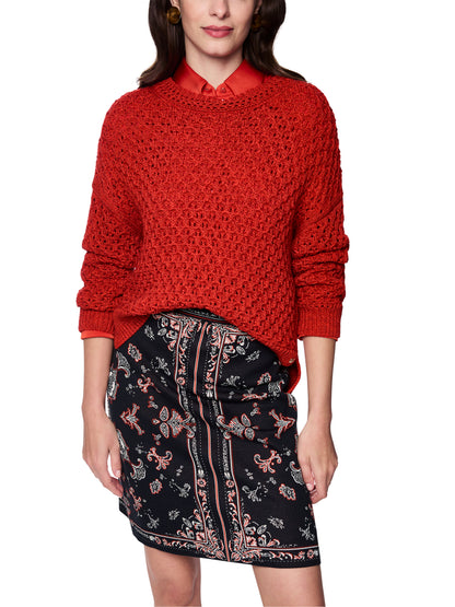 Person wearing a red textured sweater and patterned black skirt on a white background