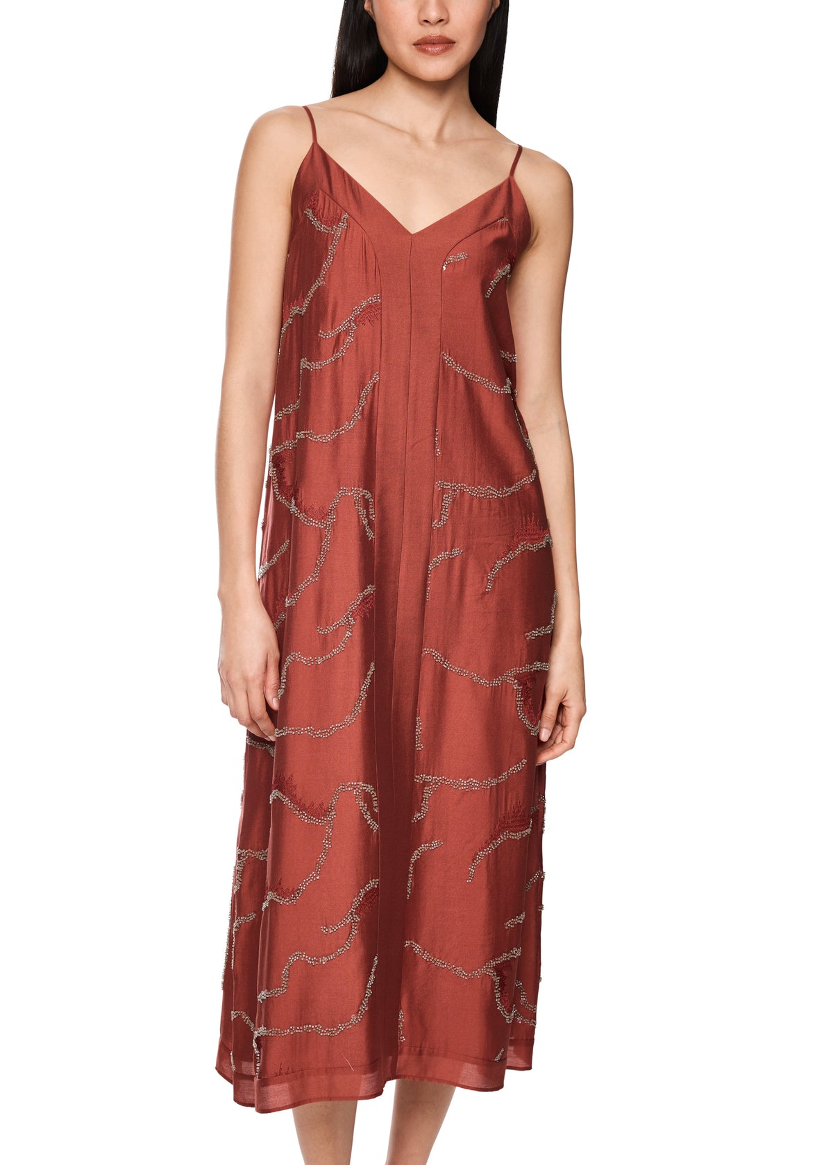 Woman wearing a rust-colored dress with thin straps on a white background
