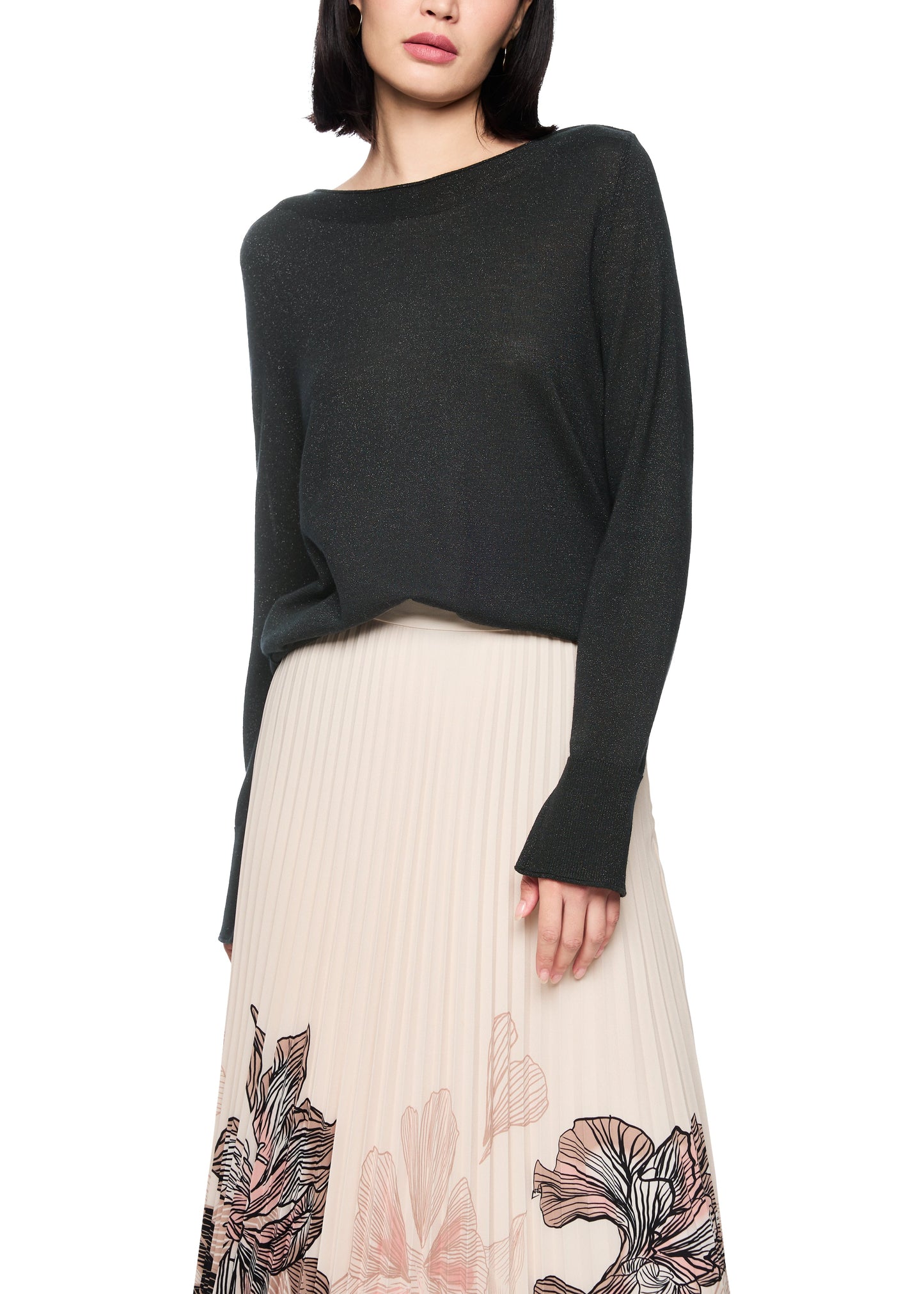 Woman wearing a black sweater and beige skirt with floral patterns on a white background