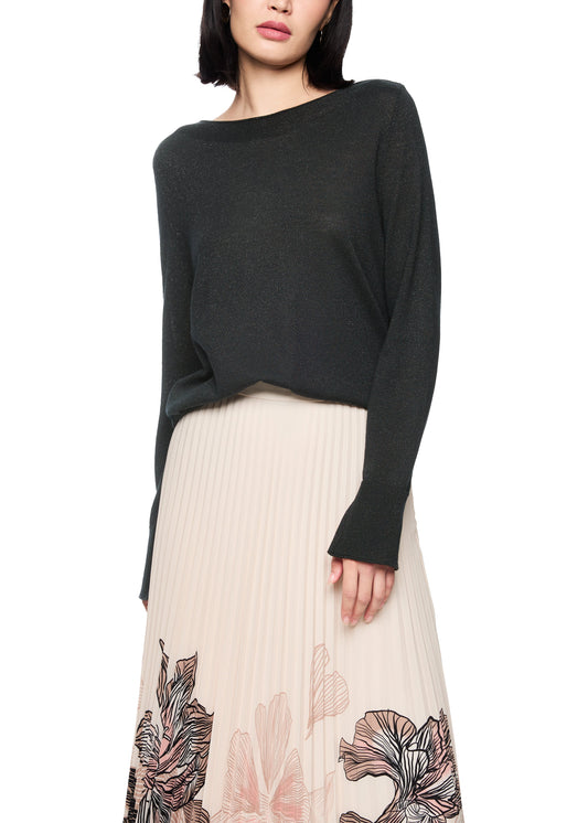 Woman wearing a black sweater and beige skirt with floral patterns on a white background