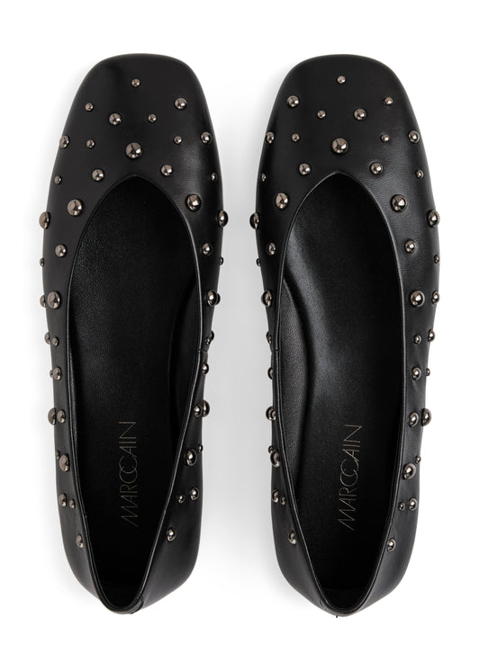 Black studded flats with 'Marcoclin' branding on a white background