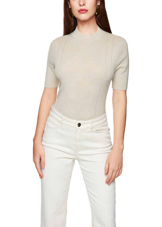 Woman wearing a beige short-sleeve top and white pants on a white background