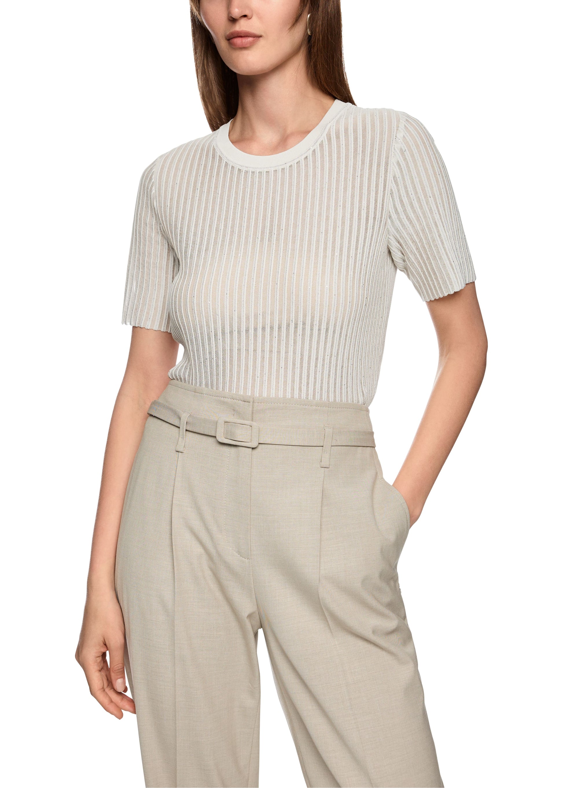 Woman wearing a white ribbed top and beige pants on a white background