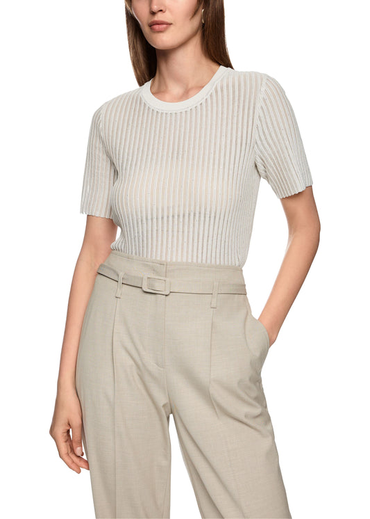 Woman wearing a white ribbed top and beige pants on a white background