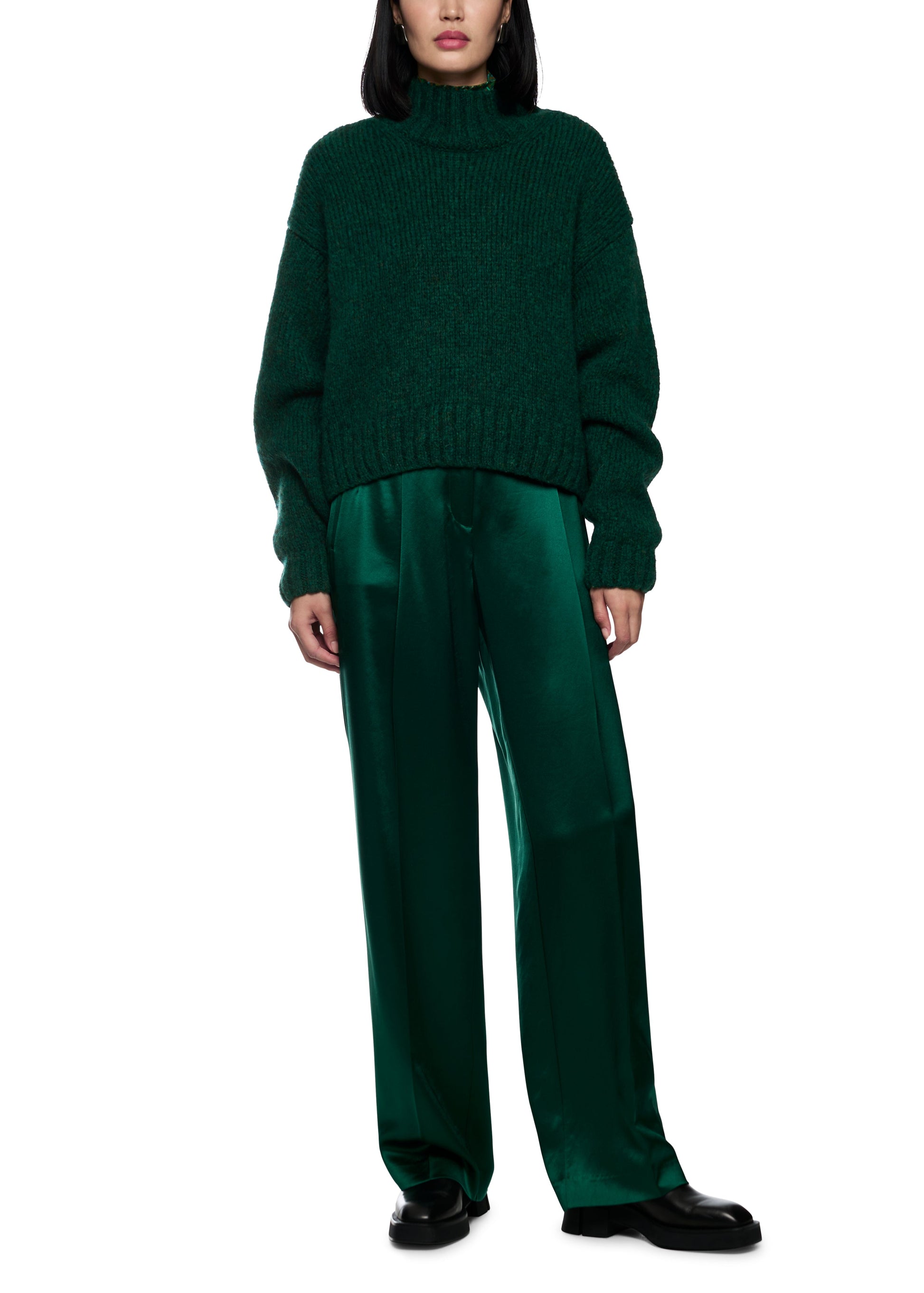 Person wearing a green sweater and pants on a white background