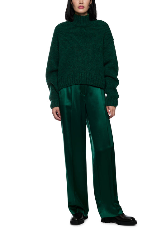 Person wearing a green sweater and pants on a white background