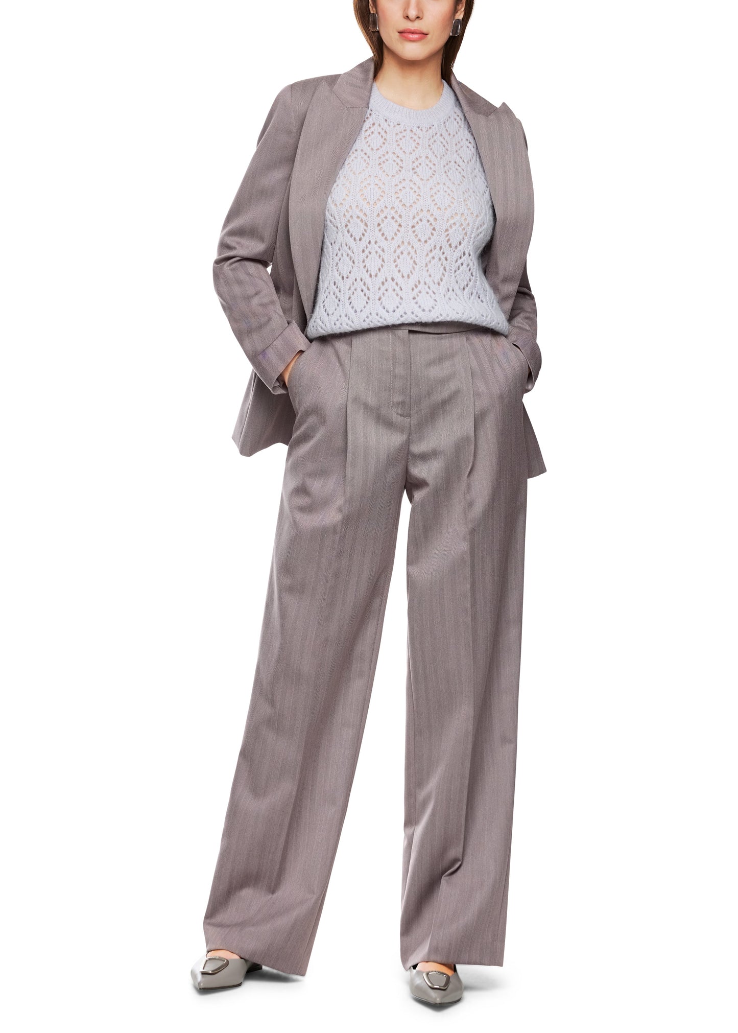 Woman wearing a gray suit with a white lace top on a white background
