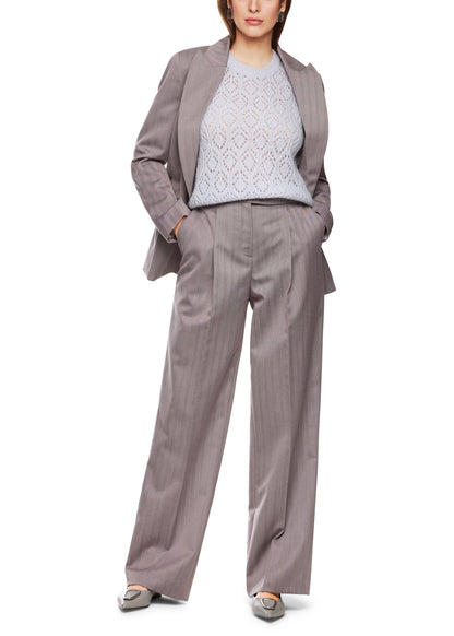 Woman wearing a gray suit with a white lace top on a white background