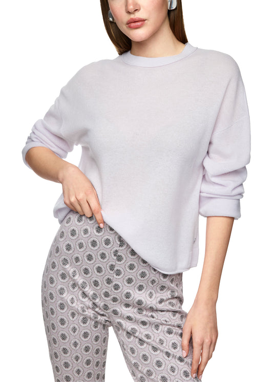 Woman wearing a light gray sweatshirt and patterned pants on a white background