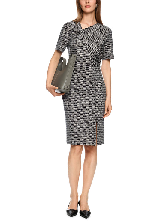 Woman wearing a patterned dress holding a clutch on a white background