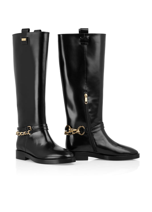 Pair of black knee-high boots with gold chain details on a white background