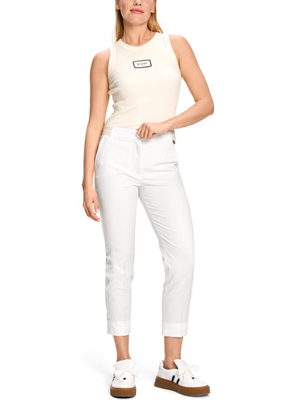 Woman wearing a white sleeveless top and pants on a white background