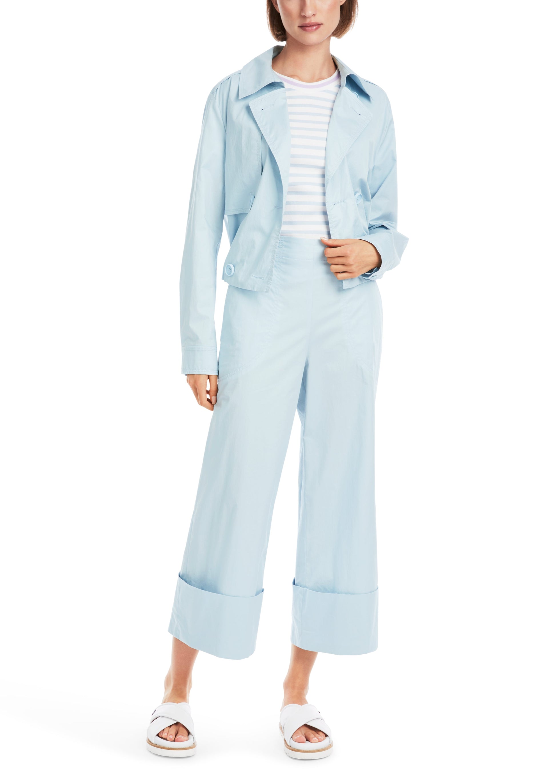 Person wearing a light blue outfit with a jacket and wide-leg pants on a white background