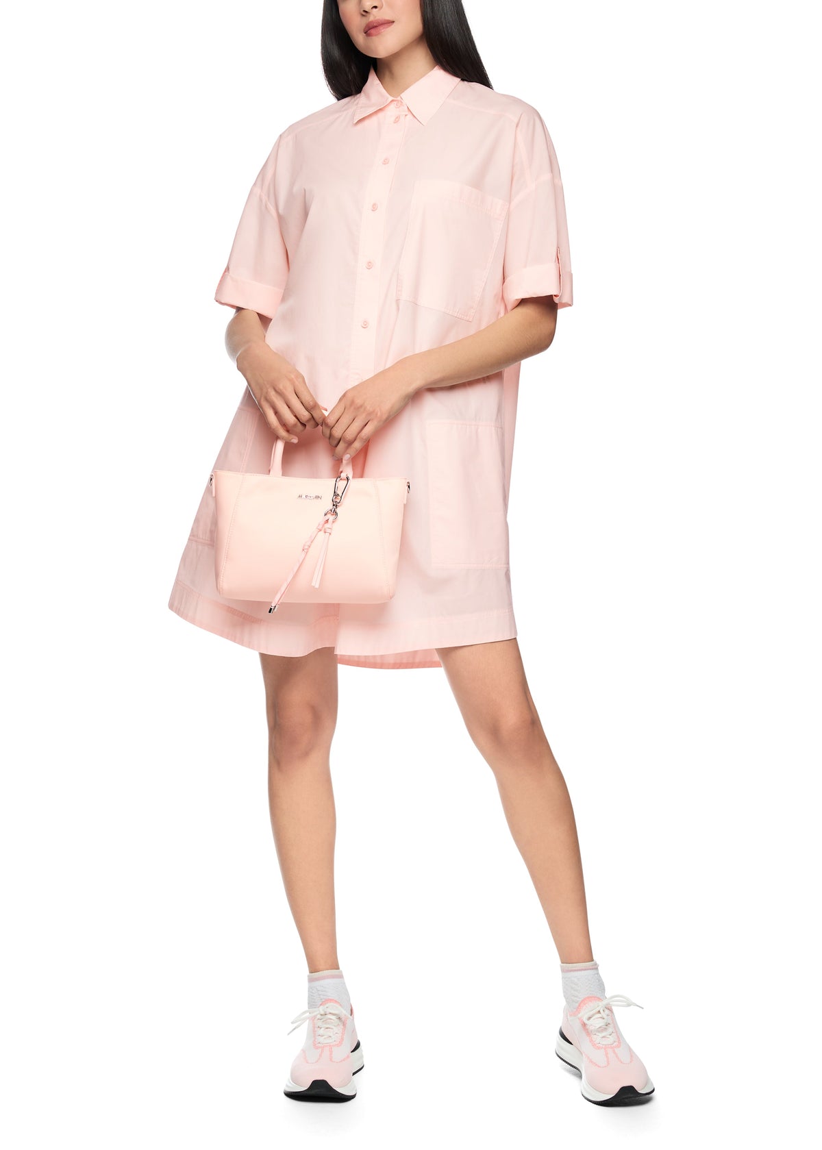 Person wearing a pink dress holding a matching handbag on a white background