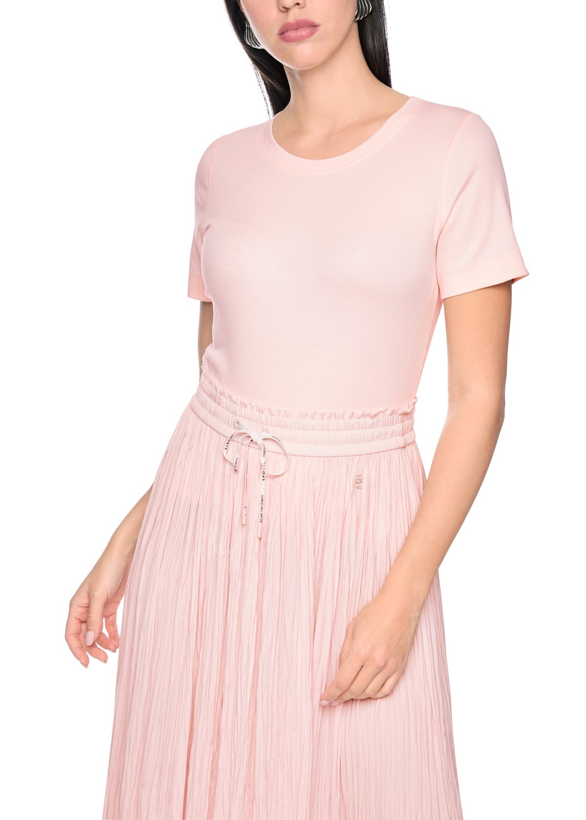 Woman wearing a pink dress with a plain white background