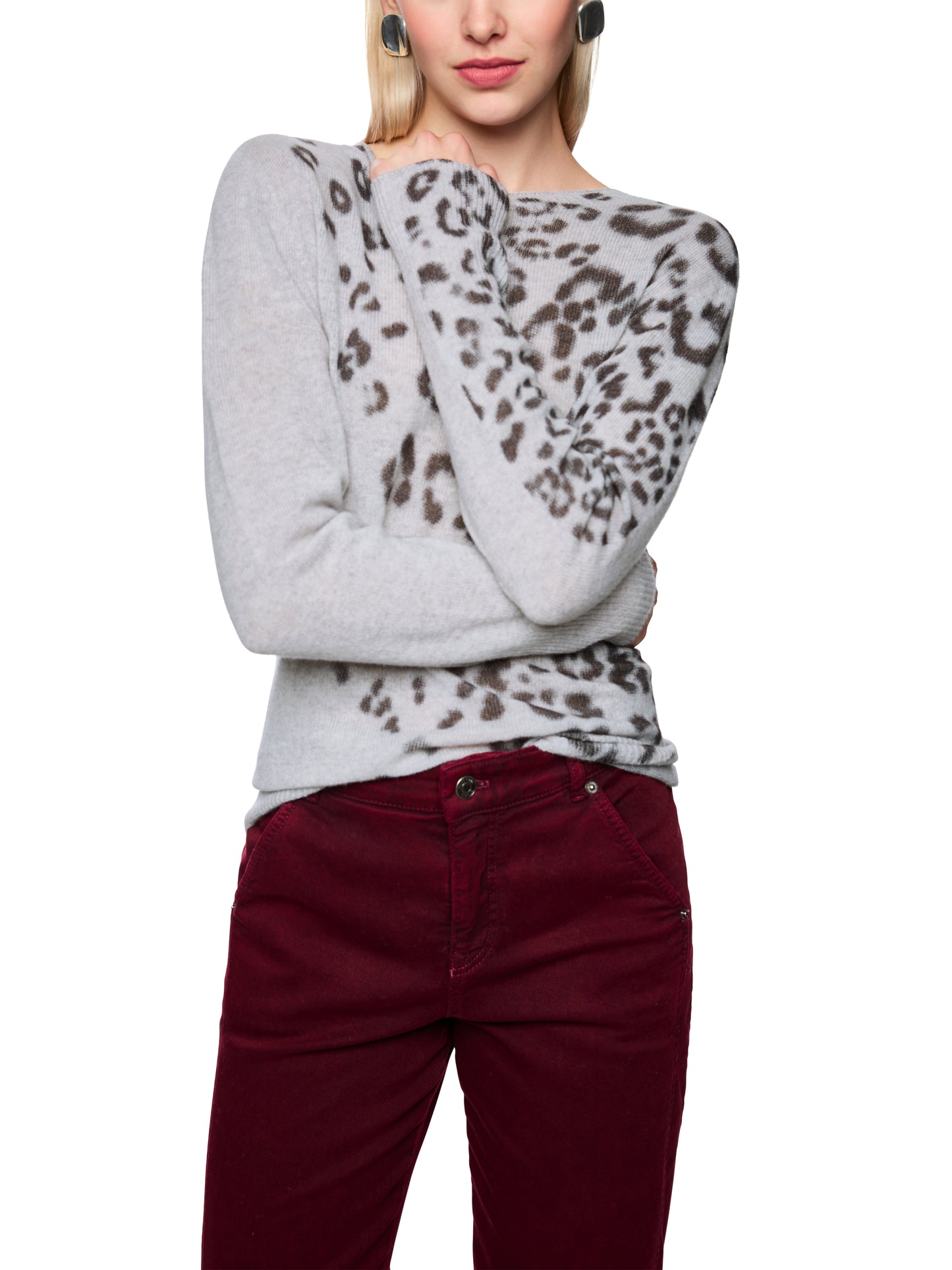 Person wearing a gray sweater with leopard print sleeves and red pants on a white background